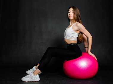 Atletik ve güçlü genç kadın bazı egzersiz fitness Ball siyah bir arka plan yapmak