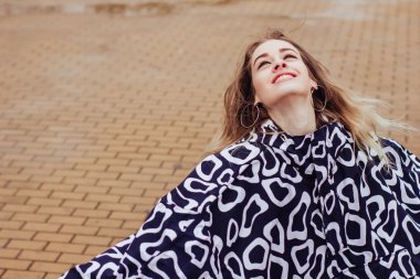 Yağmurluk ve lastik çizmeli şık kadın su birikintilerinde yürür ve eğlenir