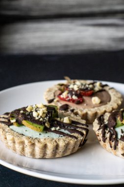 Beyaz tabakta çiğ vegan tartlets. Sağlıklı tatlılar, yakın