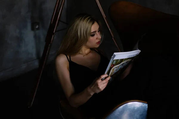 雑誌と椅子に座っている美しいスリムな若い女性 — ストック写真