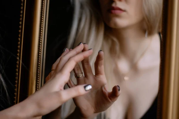 Aynanın yanında siyah bir arka plan üzerinde poz güzel ince genç kadın