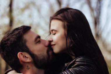 Aşık genç mutlu çift gün batımında birbirlerine sarılır ve gülümserler. Aşk öpücüğü