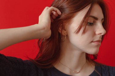 Tehlikeli derecede güzel. Kırmızı arka plan karşısında dururken bir çiçek ile çekici genç kadın. Güllü kadın