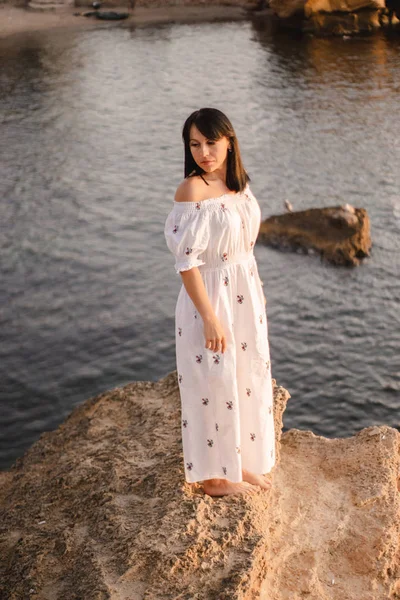 güzel genç brunete kadın sahilde güzel bir görünüm sahiptir ve iyi bir gündoğumu zamanı vardır. Rahatla