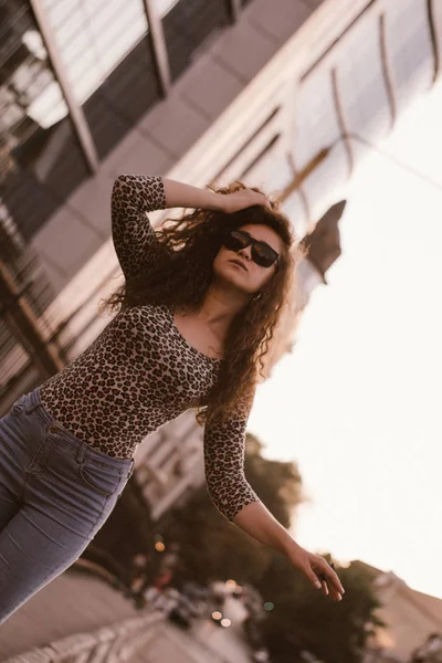 屋外で微笑み 日没時に街の通りを歩く幸せな巻き毛の若い女性 — ストック写真