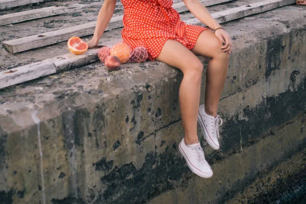 巻き毛とエキゾチックな果物と赤いドレスを着てメイクアップ若い女性のストリートファッションショット ビーチの背景 — ストック写真