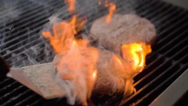 Kuchař vaří hovězí placku na burger na horkém grilu a převrátí řízek s špachtlí