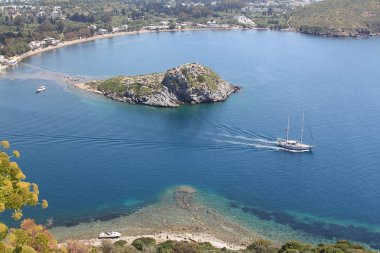 Gümüşlük Körfezi 'nde Tavşan Adası 'nın havadan yüksek açı görünümü, Bodrum. Türkiye 'de bir sahil köyü ve balıkçılık limanı olan Gümüşlük, Myndos antik kentinin kalıntıları üzerinde yer almaktadır.