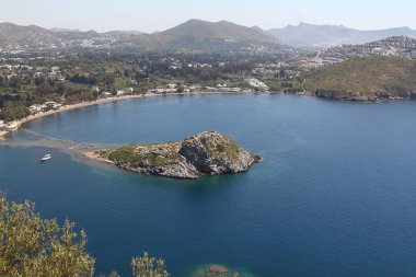 Gümüşlük Körfezi 'nde Tavşan Adası 'nın havadan yüksek açı görünümü, Bodrum. Türkiye 'de bir sahil köyü ve balıkçılık limanı olan Gümüşlük, Myndos antik kentinin kalıntıları üzerinde yer almaktadır.