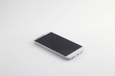 Beyaz arka planda izole edilmiş beyaz cep telefonu. Telefon masanın üstünde. Parlak telefon ekranı. Parlak yeni akıllı telefon. Cep telefonuyla konuşuyor.