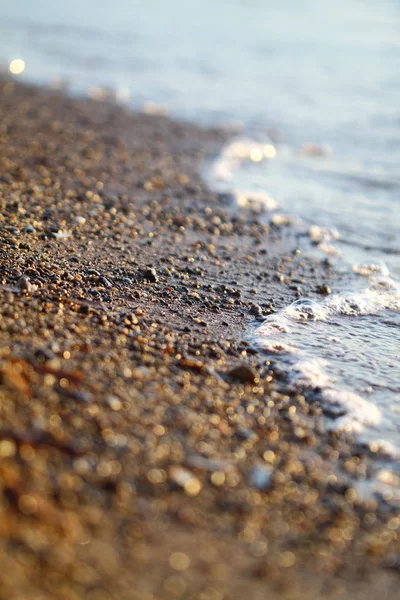 美しい黄金の夕日を背景にビーチで湿った海の砂 日没時に海岸の海の砂を閉じます 夕日の背景にビーチで黄金のぬれた砂 — ストック写真