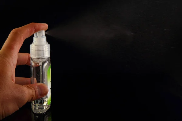 A Person\'s Hand Spraying Breath Freshener On Black Background