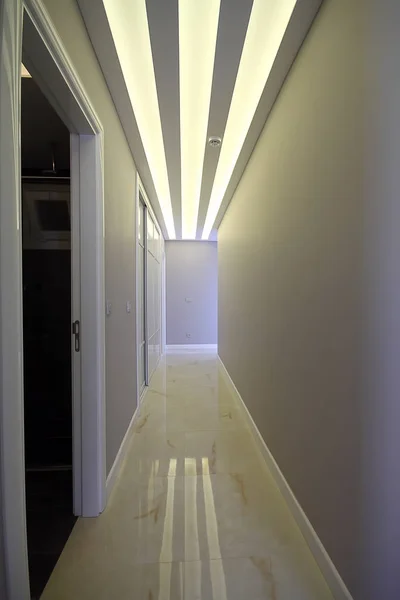 A long corridor with doors at the sides and a light at the end of the corridor