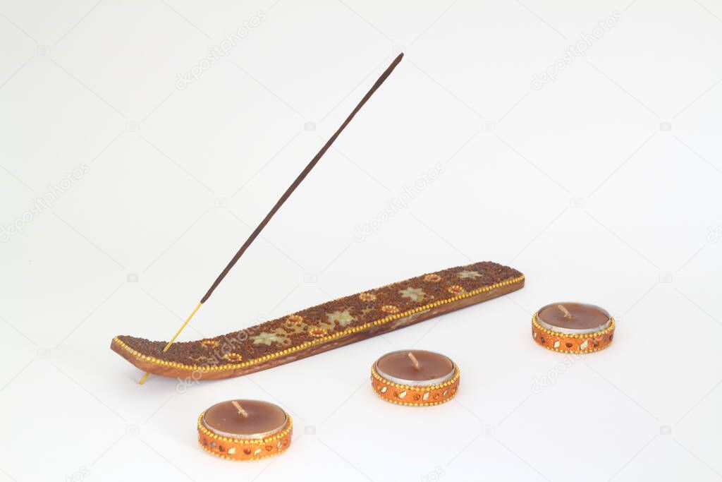 Candle and incense stick on a wooden plate with white background