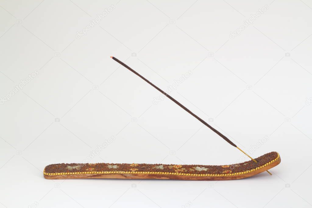  An incense stick on a wooden holder on a white background