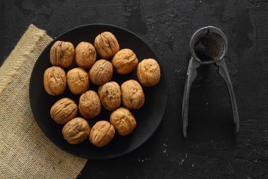 Siyah arka planda fındıkkıran ile ceviz, üst görünüm.