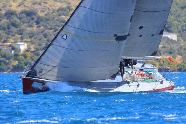 Bodrum, Hindi. 06 Nisan 2024: Ege Denizi 'nin mavi sularında, ünlü tatil beldesi Bodrum' un kıyılarında yelkenliler rüzgarlı havada yelken açıyor.