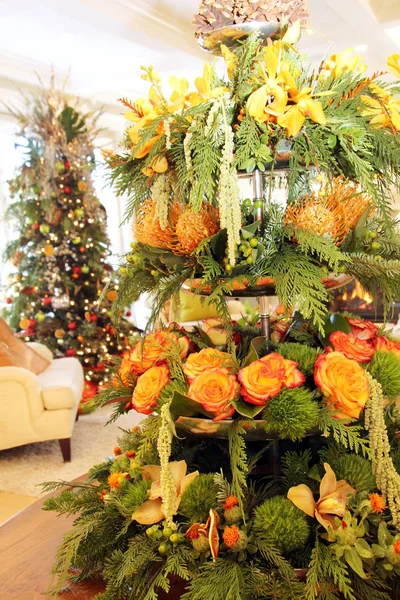 美丽的客厅圣诞花卉安排与玫瑰和常绿弓 背景中可见的圣诞树 — 图库照片