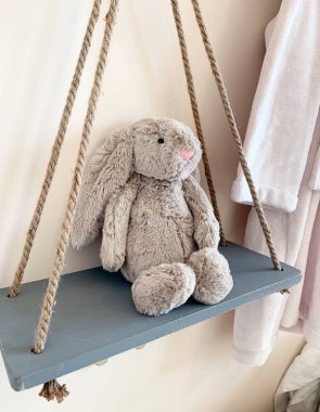 Stuffed animal on a swing in a child's bedroom. Cute cuddly bunny rabbit toy.  clipart