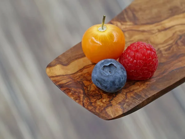 Nahaufnahme von Himbeeren, Blaubeeren und Physalis-Beeren auf Holzgrund mit Kopierraum — Stockfoto