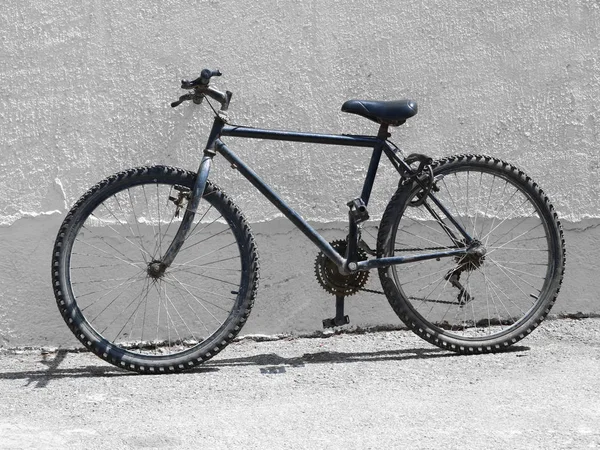 Svart, gammel sykkel, terrengsykkel ved siden av en hvit vegg – stockfoto