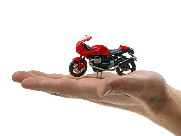 Adam avucunun içinde kırmızı bir motosiklet tutuyor. Beyaz arka planda izole edilmiş, sigorta kavramı.