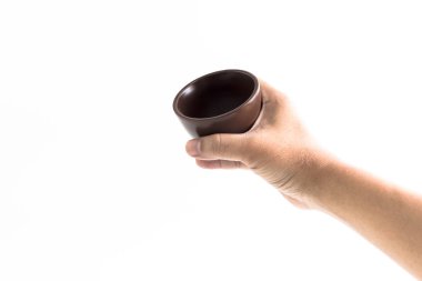 Adamın elini beyaz arka plan üzerinde kase seramik izole kahverengi seramik bardağı götürüyor