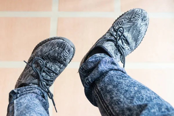 Foot of man who is stepping on his left foot while wearing the gray shoes with stripes pattern background