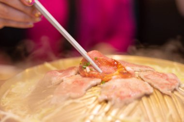 Domuz dilim, kadın h ile kavisli pirinç tava üzerinde ızgara oldu