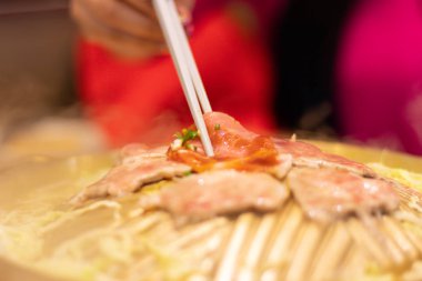 Domuz dilim, kadın h ile kavisli pirinç tava üzerinde ızgara oldu