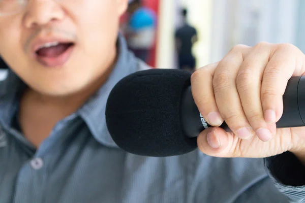 Microfone preto em uma mão de homem — Fotografia de Stock