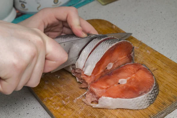 female hand cuts red fish