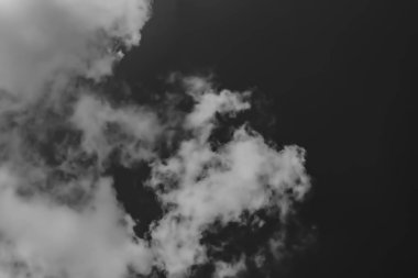 karanlık gökyüzüne karşı beyaz bulutlar. Monokrom