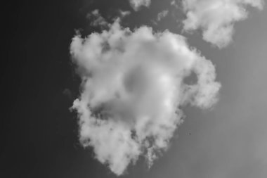 karanlık gökyüzüne karşı beyaz bulutlar. Monokrom