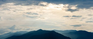 Gün batımında dağların karanlık siluetleri. Dağ manzarası