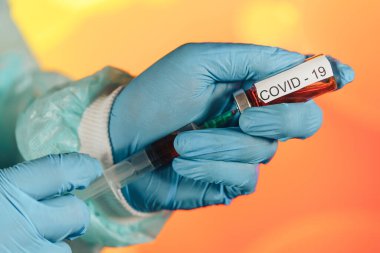 Mavi eldivenli bir sağlık görevlisi şırıngaya ampul çekiyor. Coronavirus gribine karşı tıbbi aşı. Tıbbi cam şişeleri için enjeksiyon şişesi. COVID salgını