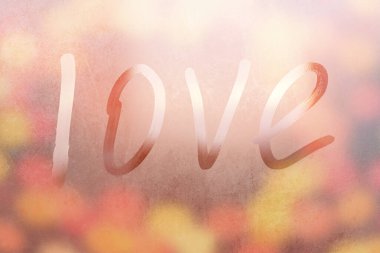 Terli bardaktaki yazıt aşkı. Renkli arka planda sisli cam bir pencereye çizilmiş aşk. Sisli camda aşkın ve mutluluğun sembolü.