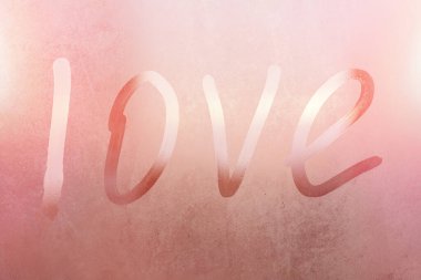 Terli bardaktaki yazıt aşkı. Renkli arka planda sisli cam bir pencereye çizilmiş aşk. Sisli camda aşkın ve mutluluğun sembolü.