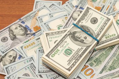 Ahşap masa arkaplan dokusunda yüzlerce dolarlık banknotlar. Bir tomar para ofis masasına saçıldı. zenginlik ve gelir kavramı