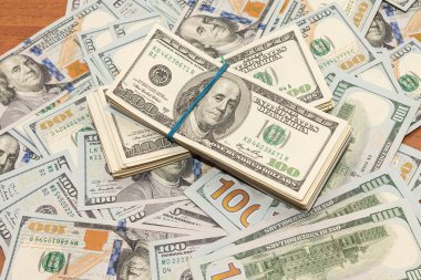 Ahşap masa arkaplan dokusunda yüzlerce dolarlık banknotlar. Bir tomar para ofis masasına saçıldı. zenginlik ve gelir kavramı