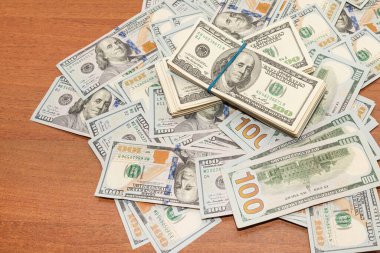 Ahşap masa arkaplan dokusunda yüzlerce dolarlık banknotlar. Bir tomar para ofis masasına saçıldı. zenginlik ve gelir kavramı