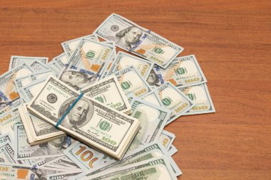 Ahşap masa arkaplan dokusunda yüzlerce dolarlık banknotlar. Bir tomar para ofis masasına saçıldı. zenginlik ve gelir kavramı