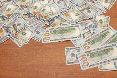 Ahşap masa arkaplan dokusunda yüzlerce dolarlık banknotlar. Bir tomar para ofis masasına saçıldı. zenginlik ve gelir kavramı