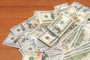 Ahşap masa arkaplan dokusunda yüzlerce dolarlık banknotlar. Bir tomar para ofis masasına saçıldı. zenginlik ve gelir kavramı