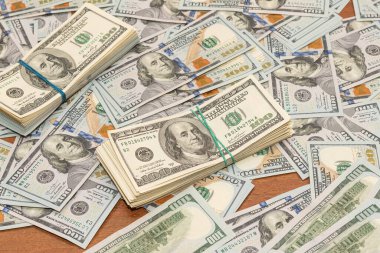 Ahşap masa arkaplan dokusunda yüzlerce dolarlık banknotlar. Bir tomar para ofis masasına saçıldı. zenginlik ve gelir kavramı