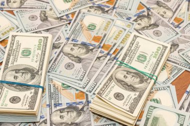 Ahşap masa arkaplan dokusunda yüzlerce dolarlık banknotlar. Bir tomar para ofis masasına saçıldı. zenginlik ve gelir kavramı