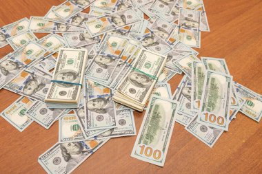 Ahşap masa arkaplan dokusunda yüzlerce dolarlık banknotlar. Bir tomar para ofis masasına saçıldı. zenginlik ve gelir kavramı