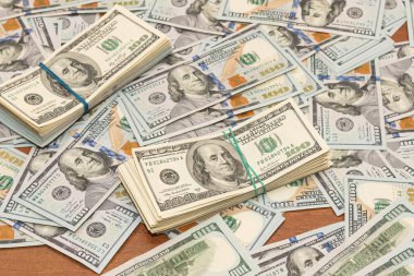 Ahşap masa arkaplan dokusunda yüzlerce dolarlık banknotlar. Bir tomar para ofis masasına saçıldı. zenginlik ve gelir kavramı