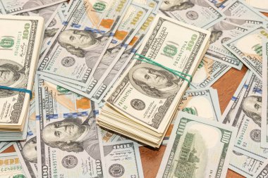 Ahşap masa arkaplan dokusunda yüzlerce dolarlık banknotlar. Bir tomar para ofis masasına saçıldı. zenginlik ve gelir kavramı