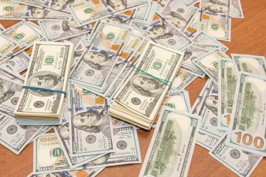 Ahşap masa arkaplan dokusunda yüzlerce dolarlık banknotlar. Bir tomar para ofis masasına saçıldı. zenginlik ve gelir kavramı